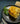 A baked cheese casserole served on a dark gray plate with parsley garnish, set on a dark textured table with a wedge of Swiss cheese and cutlery nearby.